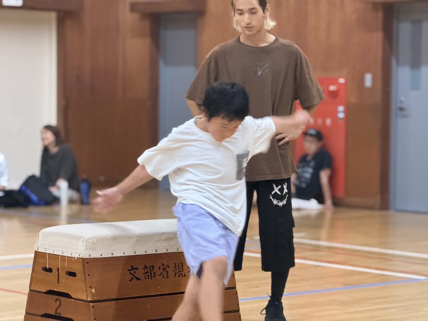 跳び箱に挑む子どもを見守るPK Guildのコーチ