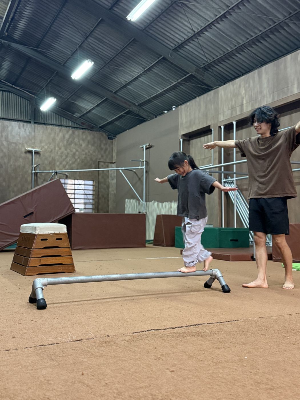 レールの上を歩く子どもと、横について見守るコーチ