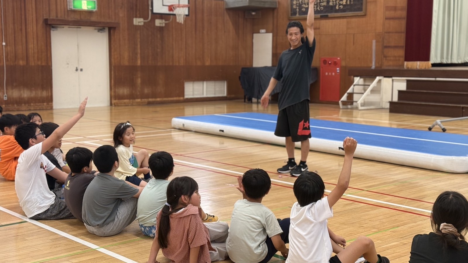 小学校の体育館で子どもたちを前に話すPK Guildのコーチ